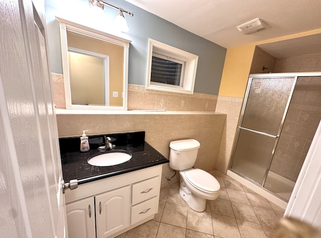 bathroom with tile walls, vanity, walk in shower, toilet, and tile patterned floors