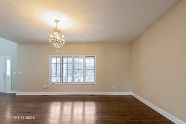 spare room featuring a notable chandelier and dark hardwood / wood-style floors