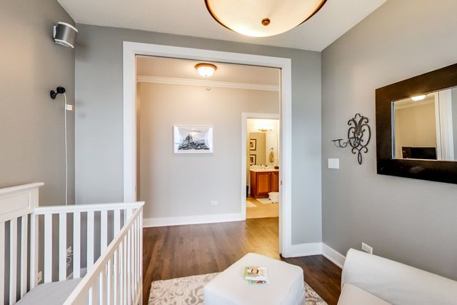 bedroom with ornamental molding, a nursery area, and dark wood-type flooring