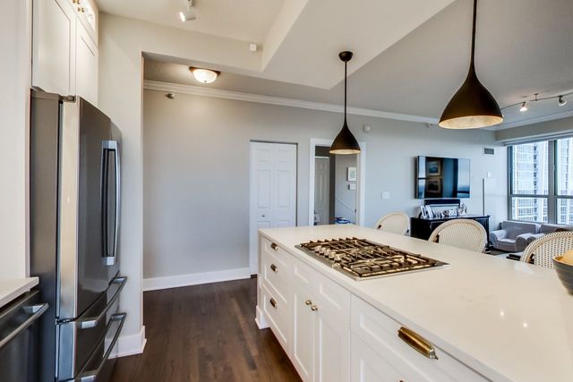 kitchen with white cabinetry, appliances with stainless steel finishes, decorative light fixtures, and dark hardwood / wood-style flooring