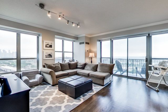 living room with dark wood-type flooring, ornamental molding, rail lighting, and plenty of natural light