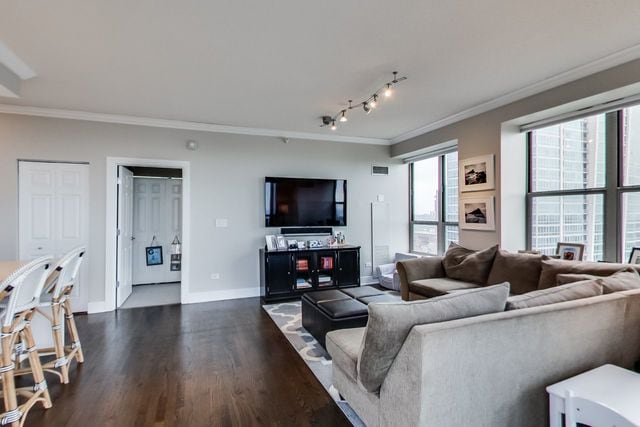 living room featuring crown molding, dark wood-type flooring, and track lighting