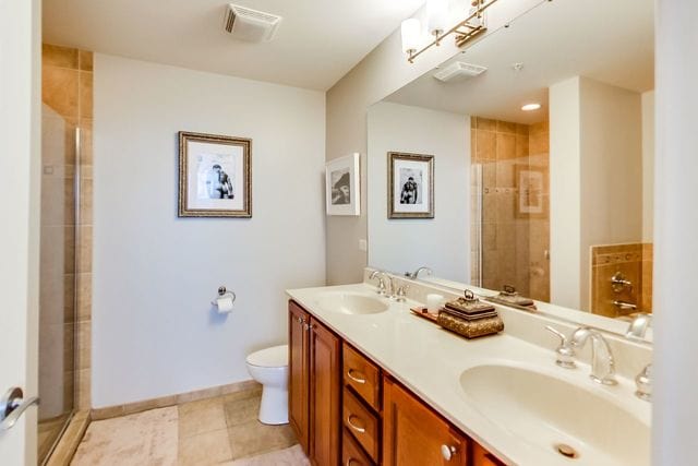 bathroom featuring vanity, toilet, tile patterned flooring, and a shower with door