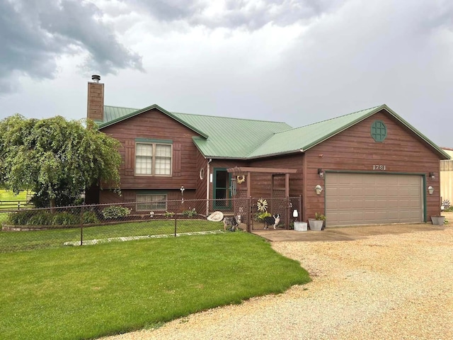 view of front of house with driveway, a chimney, metal roof, fence, and a front lawn