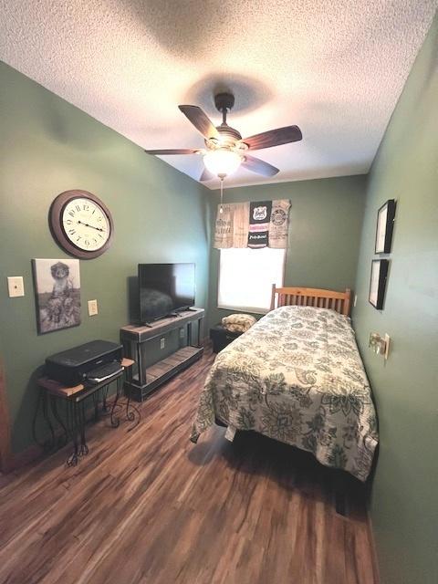 bedroom featuring ceiling fan, wood finished floors, and a textured ceiling