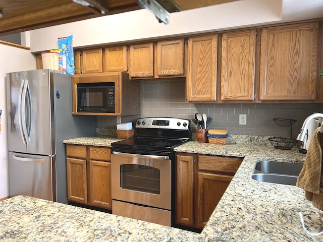 kitchen with brown cabinets, decorative backsplash, stainless steel appliances, and a sink