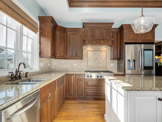 kitchen featuring sink, light stone counters, hanging light fixtures, light wood-type flooring, and appliances with stainless steel finishes