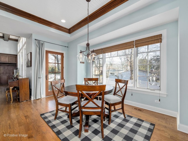 dining area featuring crown molding, light hardwood / wood-style flooring, a raised ceiling, and a chandelier