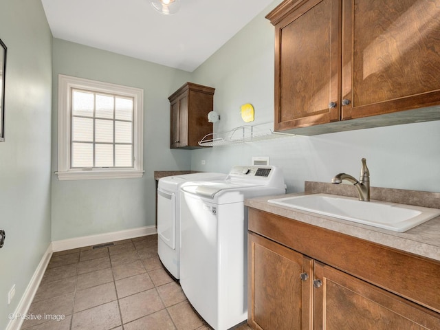 washroom with cabinets, sink, washing machine and dryer, and light tile patterned floors