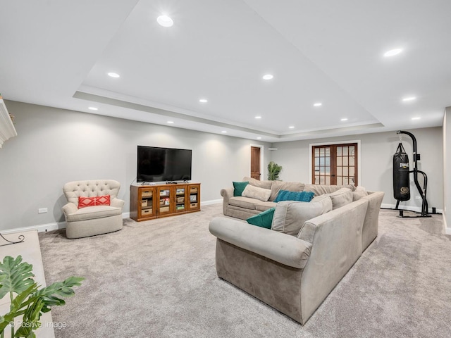 living room featuring a raised ceiling, light colored carpet, and french doors