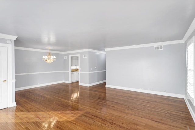 unfurnished room with an inviting chandelier, ornamental molding, and dark hardwood / wood-style floors