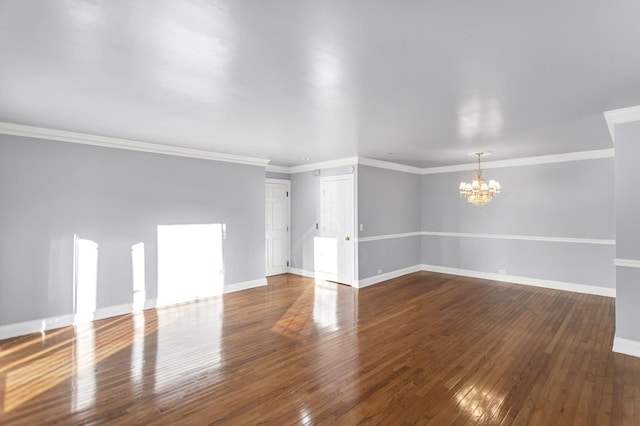 empty room featuring ornamental molding, dark hardwood / wood-style floors, and a chandelier