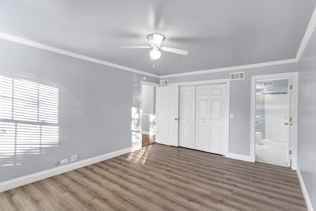 unfurnished bedroom with crown molding, wood-type flooring, a closet, and ensuite bathroom