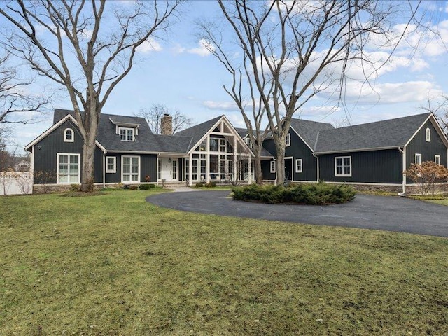 view of front of property with a front lawn, a chimney, and aphalt driveway