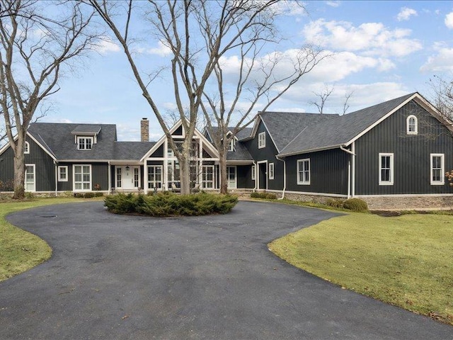 view of front facade with driveway, a chimney, and a front yard