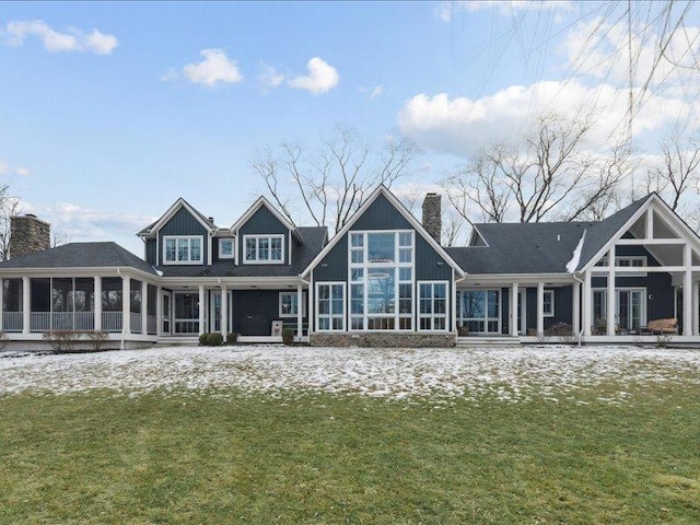 rear view of house featuring a yard, a chimney, and a sunroom