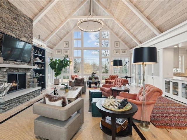 living area with a fireplace, high vaulted ceiling, wood ceiling, wood finished floors, and a chandelier