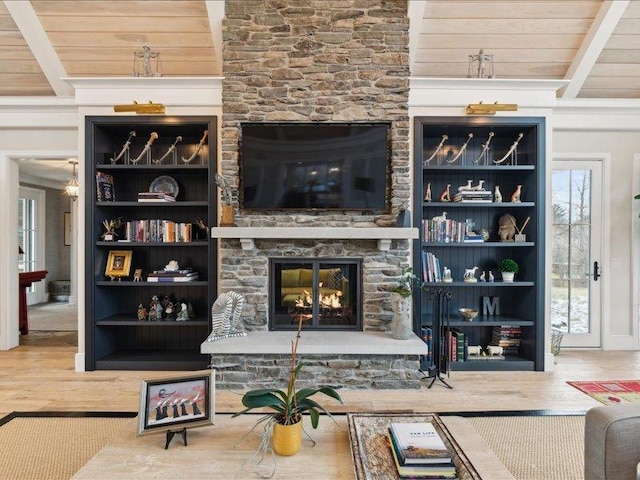 living room with wooden ceiling, beam ceiling, wood finished floors, and a stone fireplace