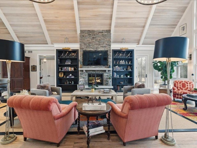 living room with visible vents, a stone fireplace, lofted ceiling with beams, and wood finished floors