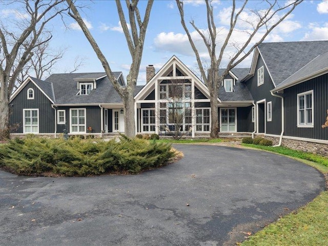 rear view of house featuring a chimney and aphalt driveway