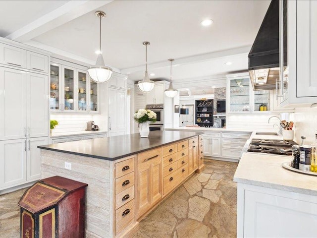 kitchen featuring glass insert cabinets, appliances with stainless steel finishes, stone finish floor, a center island, and white cabinetry