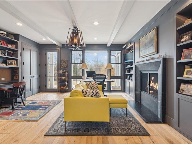 living area featuring recessed lighting, a premium fireplace, wood finished floors, built in features, and beam ceiling