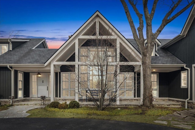 view of front facade with a shingled roof and a porch