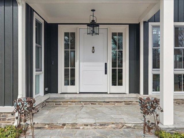 property entrance with covered porch, stone siding, and board and batten siding