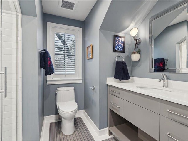 bathroom featuring toilet, vanity, visible vents, baseboards, and a shower