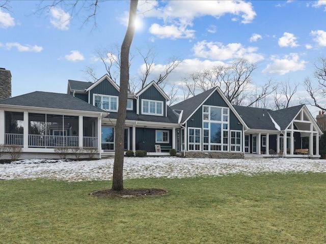 back of house featuring a lawn, a chimney, and a sunroom