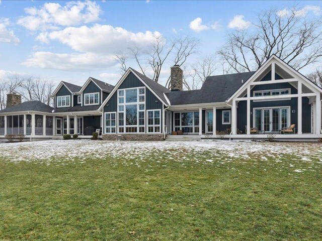 rear view of property with a lawn, a chimney, board and batten siding, and a sunroom