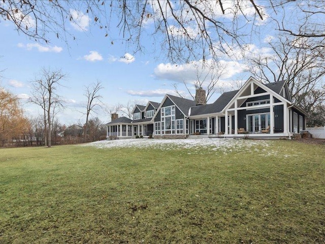 back of property featuring a sunroom, french doors, a lawn, board and batten siding, and a chimney