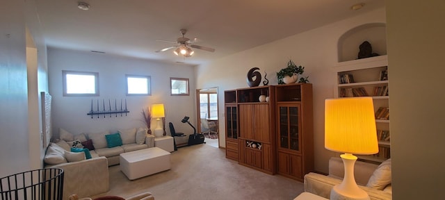 living room featuring light colored carpet, ceiling fan, and built in shelves