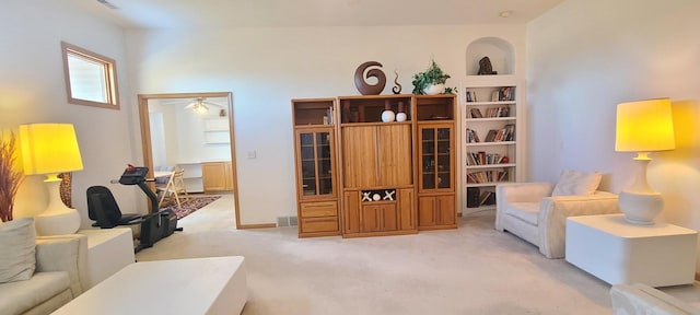 living room featuring light carpet, ceiling fan, and built in shelves