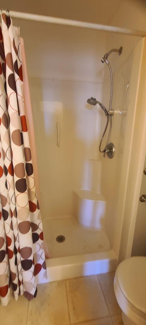 bathroom featuring tile patterned flooring, a shower with curtain, and toilet