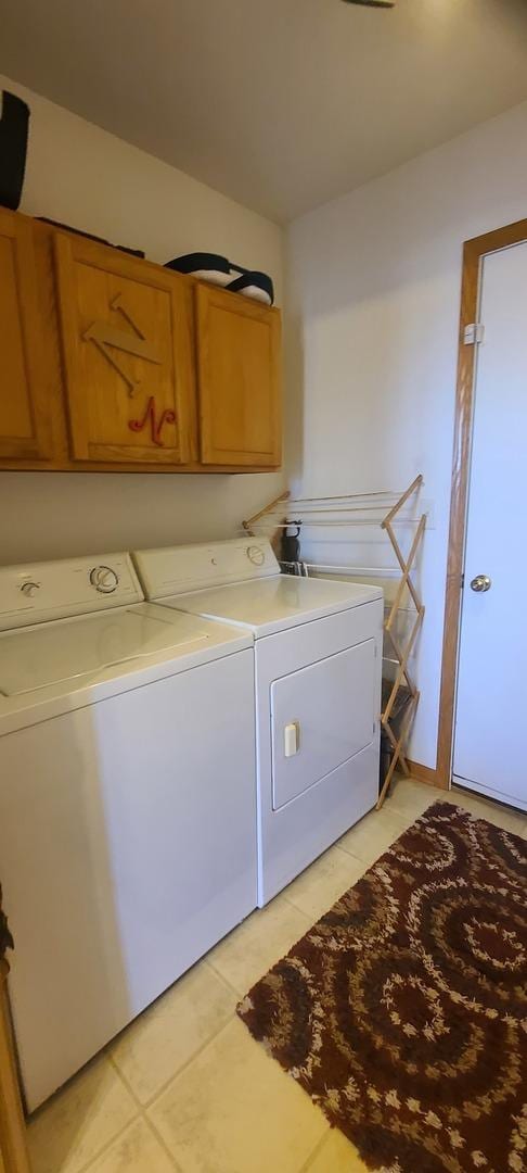 laundry area featuring cabinets, light tile patterned flooring, and washer and dryer