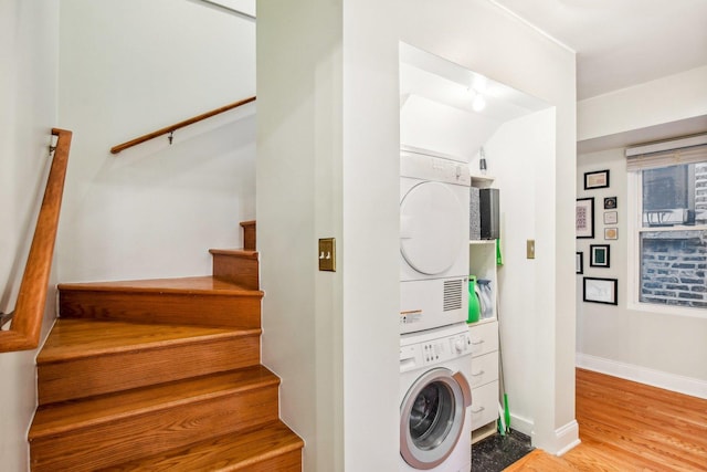 laundry area with stacked washer and dryer and wood-type flooring