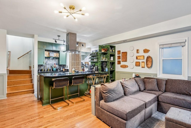 living room featuring a notable chandelier, bar area, and light wood-type flooring