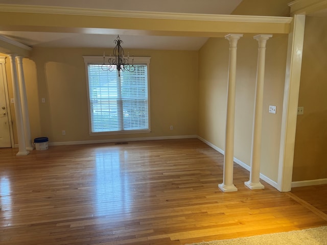 unfurnished dining area with decorative columns, ornamental molding, an inviting chandelier, and light hardwood / wood-style floors