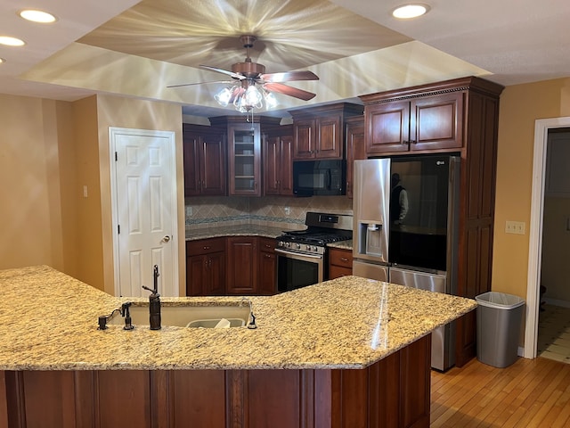 kitchen featuring appliances with stainless steel finishes, sink, decorative backsplash, ceiling fan, and light stone countertops