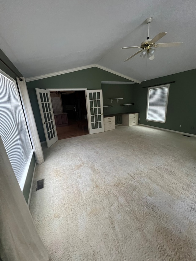 unfurnished living room featuring ceiling fan, carpet floors, vaulted ceiling, and a wealth of natural light