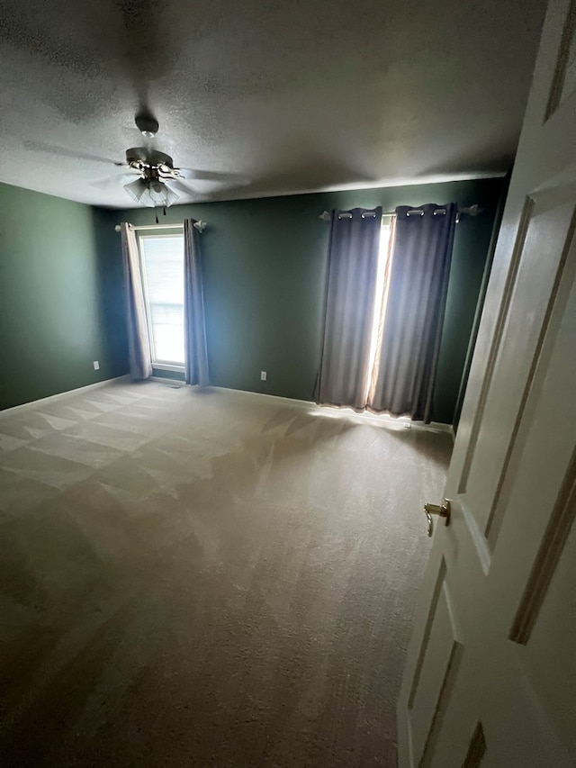 unfurnished room with ceiling fan, carpet, and a textured ceiling