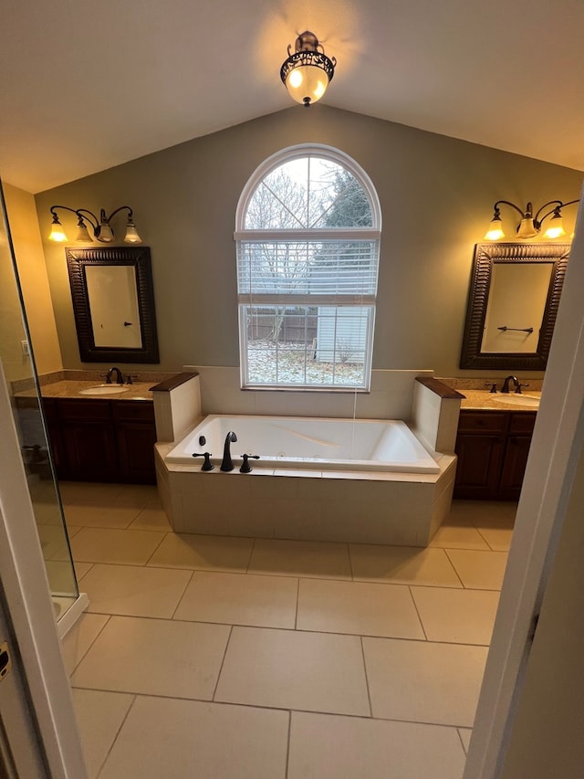 bathroom with vanity, vaulted ceiling, tile patterned floors, and tiled bath