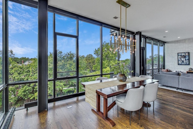 dining space with a baseboard heating unit, a wall of windows, wood-type flooring, and plenty of natural light