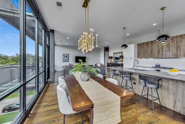 dining area with dark hardwood / wood-style flooring, sink, a fireplace, and a wall of windows