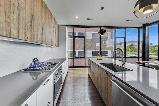 kitchen with sink, decorative light fixtures, appliances with stainless steel finishes, expansive windows, and white cabinets