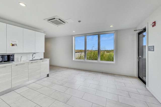 kitchen featuring sink, light tile patterned floors, and white cabinets