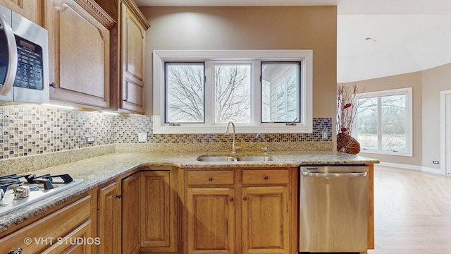 kitchen featuring light stone countertops, appliances with stainless steel finishes, sink, and a wealth of natural light