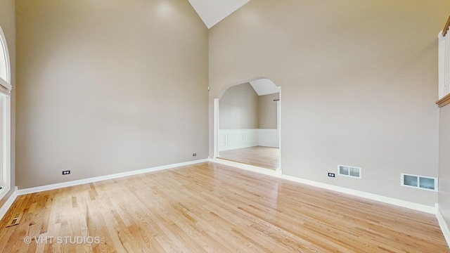 spare room with high vaulted ceiling and light hardwood / wood-style floors