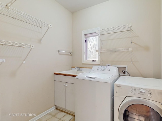 clothes washing area with sink, washing machine and dryer, and cabinets